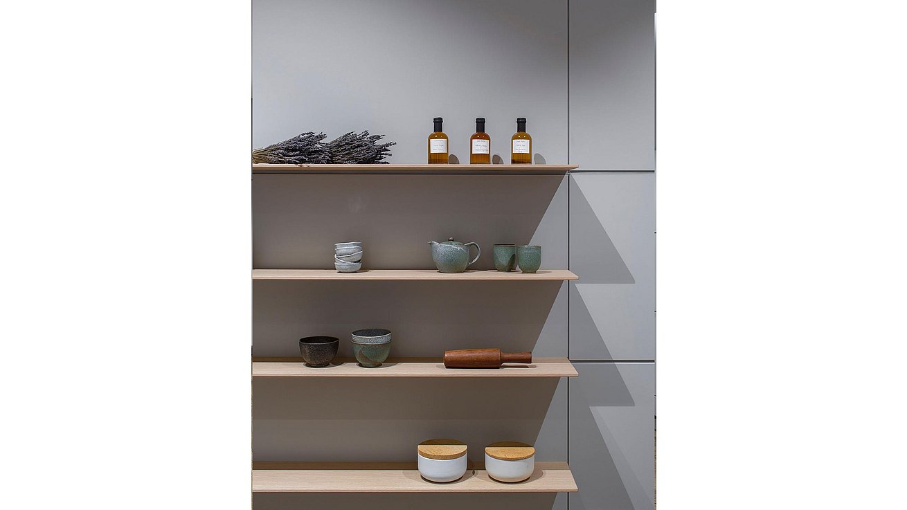 Detail of floating oak shelves presenting special ceramics and bottles of oil.